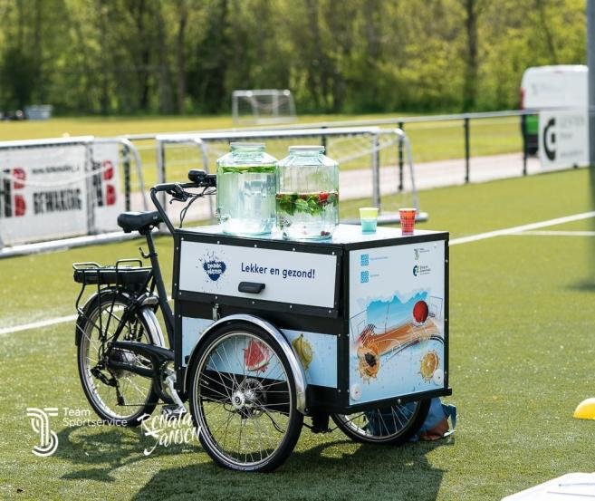 Afbeelding: foto van de waterbar (fiets met drinkvoorziening) op een sportveld